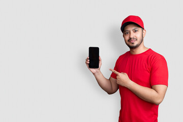 Delivery man employee in red cap blank t-shirt uniform hold black mobile phone application isolated...
