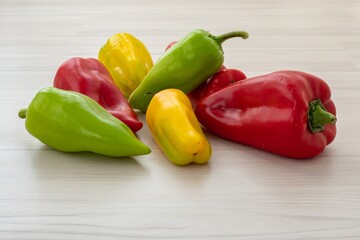 Colorful bell peppers (Capsicum annuum) vegetables. Yellow green red paprika on light wooden background. Bio food for preparing healthy nourishment. Fresh organic products in bright different colors.