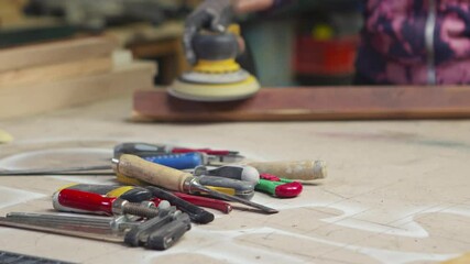 paning over tools in a carpenters workshop using orbital sander