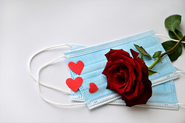 Disposable medical face mask with red heart and red rose on white background. Safe Valentine's Day during the coronavirus pandemic.