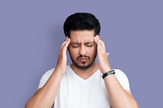 Close up photo of young age man perfect appearance arms hands on forehead. Terrible pain in eyes, closed wear casual white t-shirt isolated on background