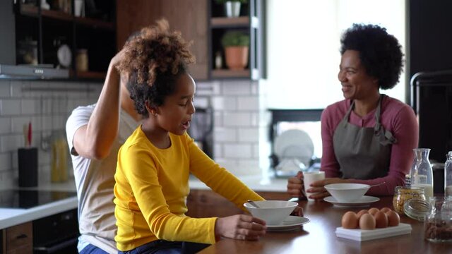 Happy family with daughter enjoying breakfast in kitchen