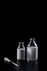 Medical glass containers isolated on black. Syringe with vaccine.