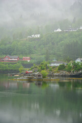 foggy mountain at a fjord with red wooden houses near Bergen in Norway