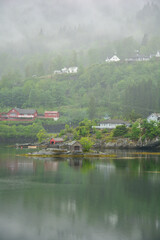 Obraz premium foggy mountain at a fjord with red wooden houses near Bergen in Norway
