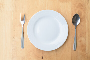Empty plate and spoon fork on table.