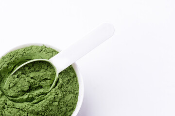 Green vegetables powder on white cup and spoon at white background isolated, copyspace