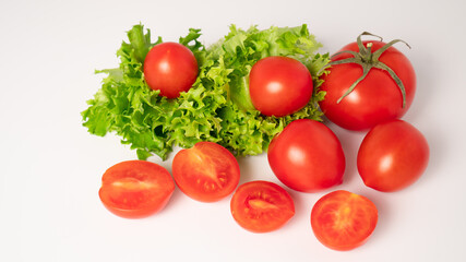 Fresh lettuces salad with fresh tomatoes isolated on white background. Ripe tomatoes scattered on the table