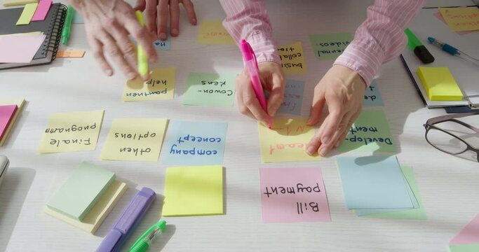 A team of business people are working on a project using notes memo post stickers. Meeting and brainstorming designers creators in the workplace. Company employees are discussing the development of a 
