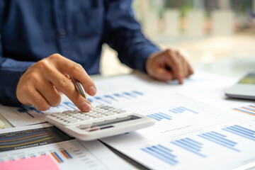 Male accountants or businessmen use a calculator and laptop to calculate investment results. And making financial reports on the desk Business finance accounting concept