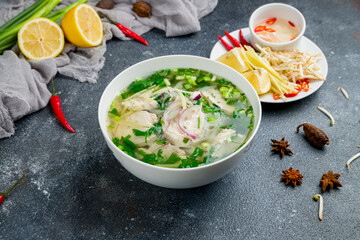 Vietnamese soup Pho GA on bowl, with chicken, green onion and spices on beautiful dark concrete table