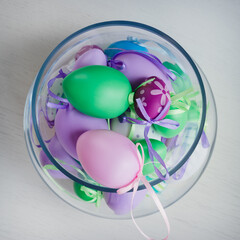 Glass vase filled with colorful Easter eggs 