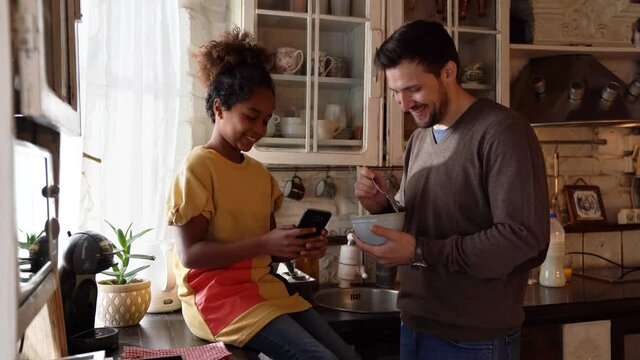 Happy single parent with daughter having fun together in kitchen