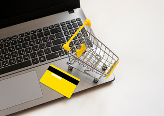 Laptop, yellow bank credit card, shopping trolley. Concept of online shopping using laptop. Business layout. Sale, black friday, discounts in the store. copy space. view from above .modern mockup