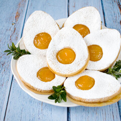 Easter egg-shaped shortbread cookies with apricot jam, sprinkled with powdered sugar.