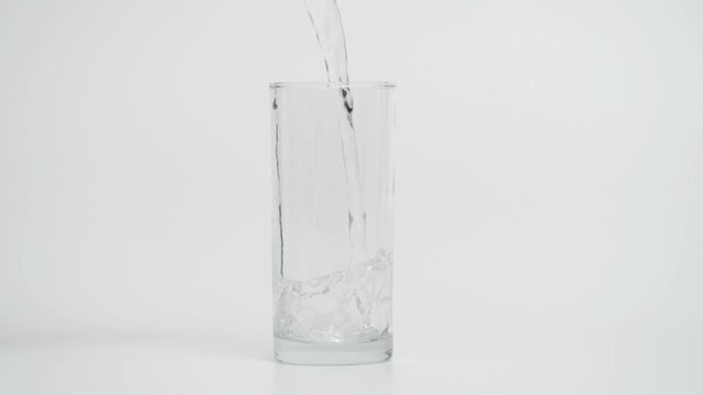 Super Slow Motion of Pouring Water in Glass with Ice, White Background