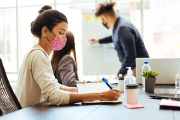 Business team wearing protective masks while meeting in the office during the COVID-19 epidemic