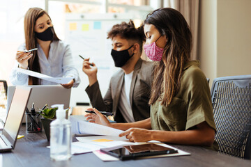 Business team wearing protective masks while meeting in the office during the COVID-19 epidemic