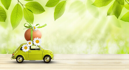 Retro car carrying an easter egg on the roof on fresh green spring foliage background.