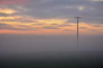 Strommast im Nebel im Sonnenuntergang bei Schweinfurt