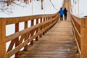 two teenagers walk together on a wooden bridge