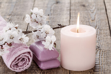 Fototapeta na wymiar Soap with towel for bathroom procedures and burning candle with flowers