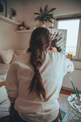 Beautiful talented female artist painting at her home.