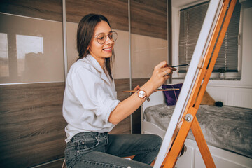Beautiful talented female artist painting at her home.