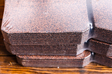 Brown bituminous shingles packed in their original packaging close-up. Roofing material to cover the roof of the house