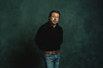 Obraz premium Man with stubble beard in black woolen sweater against grey wall