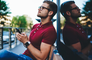 Confident young male resting in cityscape with smartphone