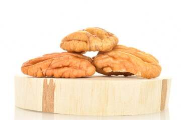 Several ripe peeled pecans on a wooden stand, close-up, isolated on white.
