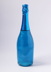 Shimmer edible glitter sparkling blue champagne in bottle on white background. Vertical format. Closeup