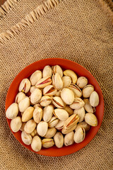 Peeled nuts in a clay plate on burlap on a wooden table.