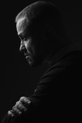 Fabulous at any age. Profile portrait of charismatic 40-year-old man standing over black background. Short haircut. Classic, smart casual style. Close up. Black and white studio shot