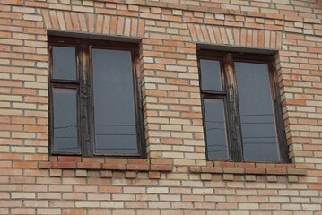 Fototapeta na wymiar two old windows on a brown brick wall of a building