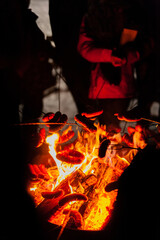 roasting sausages over fire in winter