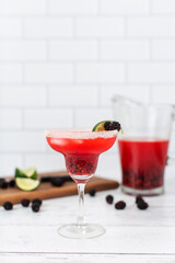 A blackberry berry margarita with fresh blackberries and limes in a margarita glass.