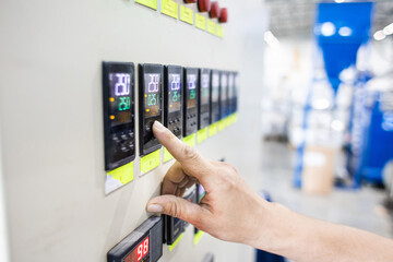A worker presses a button and starts an automatic manufacturing process in a factory
