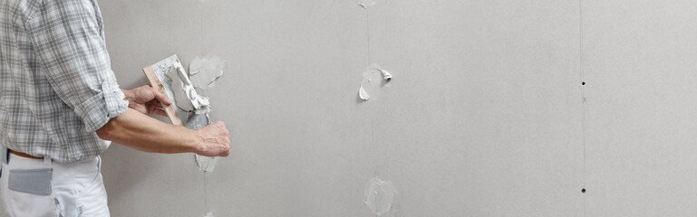 closeup hands man drywall worker or plasterer putting stucco on plasterboard wall using a trowel...