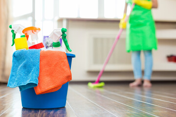 Cleaning service. Bucket with sponges, chemicals bottles and mopping stick. Rubber gloves and towel. Household equipment. a woman with a mop