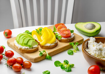 Toasts with avocado, bell pepper, tomatoes and cottage cheese white table. Healthy breakfast concept.