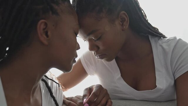 Mother and daughter sitting on sofa at home forehead close
