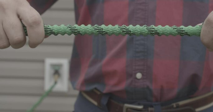 Male stretching a brand new expandable garden hose.