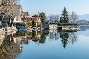 Obraz premium The town of Pusiano is reflected in the water of its lake