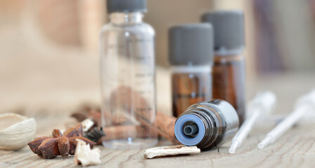 bottles of essential oil and spices  on a wooden table with pipette to extract essence