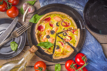 Homemade quiche Lorraine , savory pie with salmon fish, broccoli, spinach and tomatoes, on wooden table background copy space