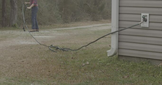Male trying to use a tangled garden hose.