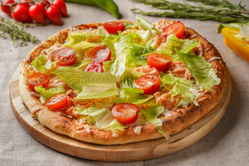 Pizza caesar on a wooden board with a beautiful vegetable background.
