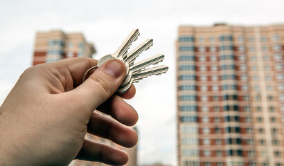 bunch of keys from an apartment in a man's hand on the background of a new building